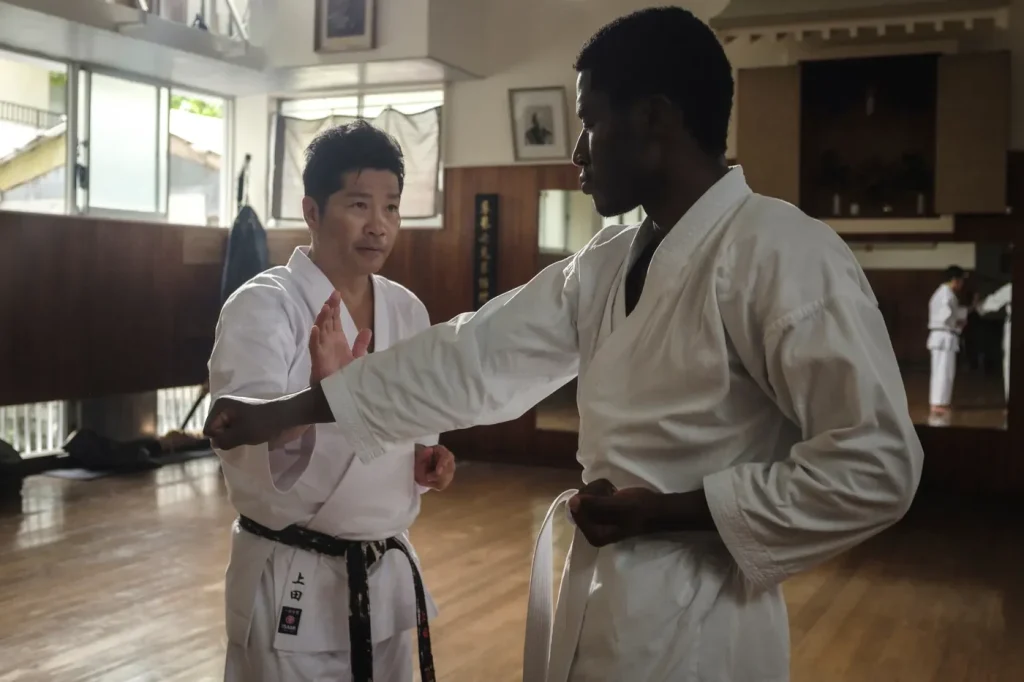 Instructor correcting a student's stance in a traditional dojo