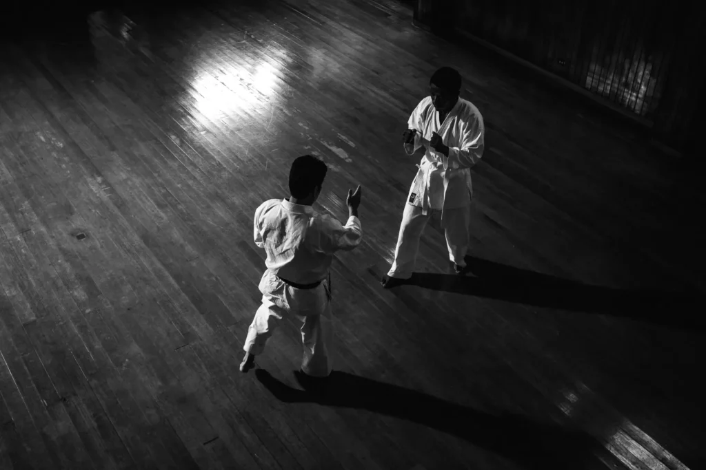 Two karateka sparring on a dojo floor