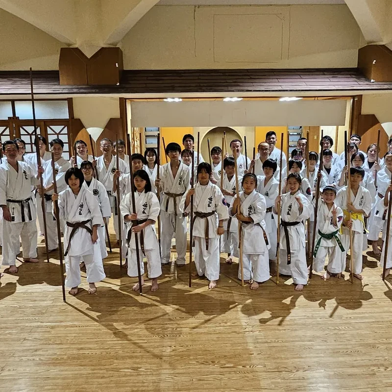Group of karateka posing with bo staffs in a dojo