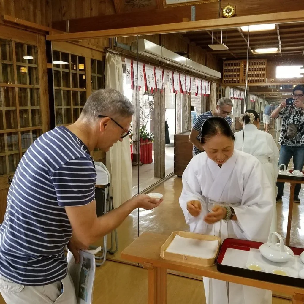 A guest respectfully receiving tea during a shrine visit