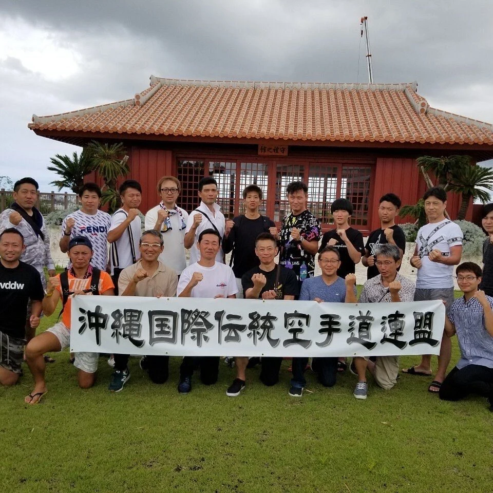 Group of Okinawan karate instructors in front of a heritage pavilion