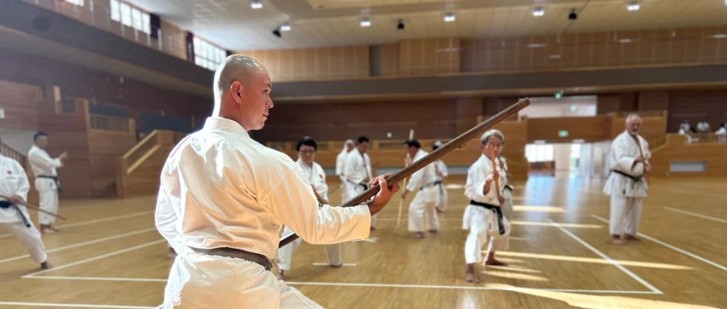 Kobudo bo-staff practice inside a large Okinawan dojo hall