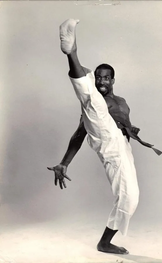 Karateka mid-air performing a jumping kick in gi