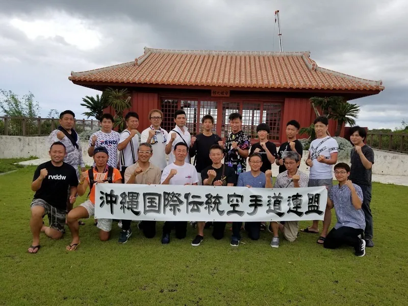 Ageshio Japan group outside an Okinawan dojo holding the Okinawa International Traditional Karate Federation banner