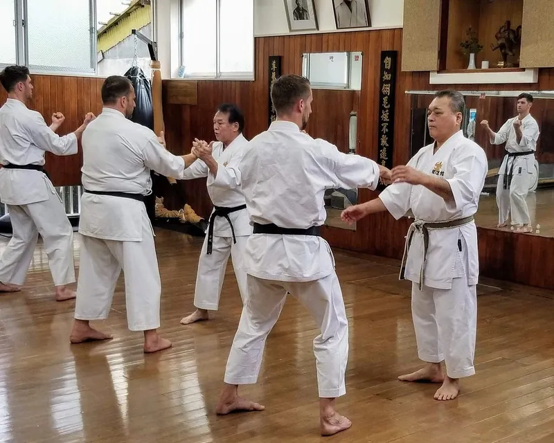 Group kumite partner drill on a wooden dojo floor in Okinawa