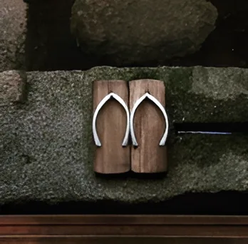A pair of traditional Okinawan wooden geta sandals resting on a stone wall